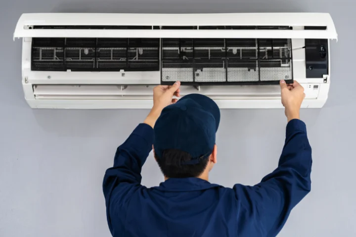Air conditioning technician in blue uniform installing split system AC unit | Icebolt Electrical